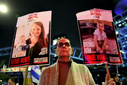 A demonstrator in Tel Aviv holds placards bearing pictures of members of the Bibas family A demonstrator in Tel Aviv holds placards bearing pictures of members of the Bibas family