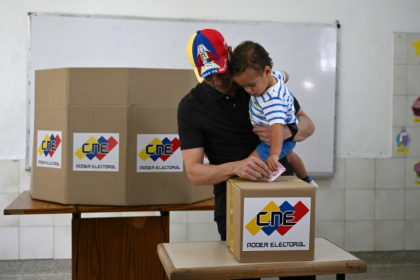 Venezuelan opposition candidate Henrique Capriles casts his vote while holding his son at a polling station in Caracas - Federico PARRA (AFP) Venezuelan opposition candidate Henrique Capriles casts his vote while holding his son at a polling station in Caracas - Federico PARRA (AFP)