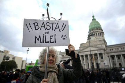 A woman holds a sign that reads in "Enough of Milei," outside of National Congress in Buenos Aires - Luis ROBAYO (AFP) A woman holds a sign that reads in "Enough of Milei," outside of National Congress in Buenos Aires - Luis ROBAYO (AFP)