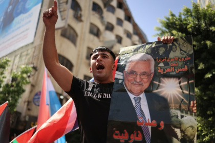 A Palestinian chants slogans in Ramallah while holding a portrait of Palestinian Authority president Mahmud Abbas - Zain JAAFAR (AFP)