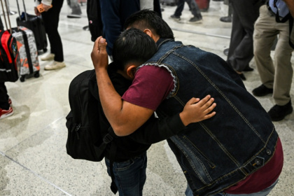 Osvaldo (R) caregiver of six-year-old US citizen Andy (L) hugs him as the boy prepares to fly to Guatemala to reunite with his recently deported father - CHANDAN KHANNA (AFP)