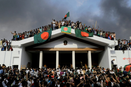 Anti-government protestors display Bangladesh's national flag as they storm Prime Minister Sheikh Hasina's palace in Dhaka on August 5, 2024 - K M ASAD (AFP)