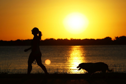 A woman walks her dog at sunset in Porto Alegre, Brazil - SILVIO AVILA (AFP)