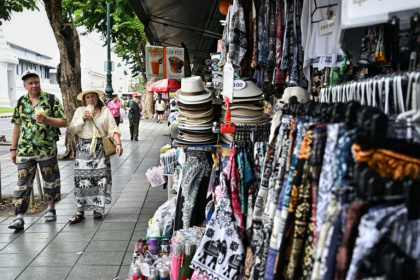 Tourists walk past souvenir shops outside the Grand Palace in Bangkok on May 20. Thailand is cutting the length of visa-free stays for tourists from more than 90 countries in an effort to curb crime involving foreign nationals - Lillian SUWANRUMPHA (AFP)