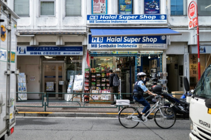 A police officer bikes past a convenience store in the Okubo–Shin area in Tokyo, a neighbourhood known for its large immigrant communities - Andrew CABALLERO-REYNOLDS (AFP)