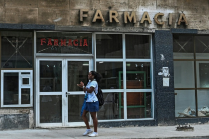 A woman walks past a pharmacy in Havana, where Cuba's communist authorities have announced an opening of sectors of its economy such as petrol stations, medicine sales and electricity generation to the private sector - YAMIL LAGE (AFP)