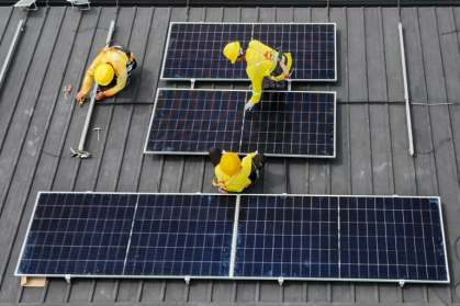 Workers instal solar panels on a roof in Carmona, in the Philippine province of Cavite - Jam STA ROSA (AFP)