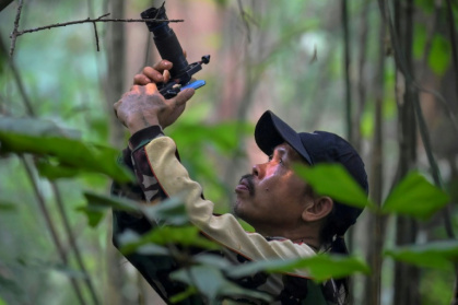 Wildlife observer and former poacher Octavius using a mobile phone equipped with a telephoto lens to take pictures of wildlife in a forest near Labian village in Kapuas Hulu, West Kalimantan - BAY ISMOYO (AFP)