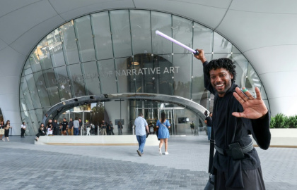 A visitor dressed as a Jedi Knight from Star Wars waves a purple lightsaber as he arrives at the Lucas Museum of Narrative Art in Los Angeles - VALERIE MACON (AFP)