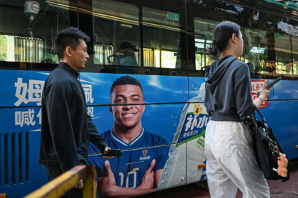 People walk past a bus featuring French football star Kylian Mbappe - Jade GAO (AFP)